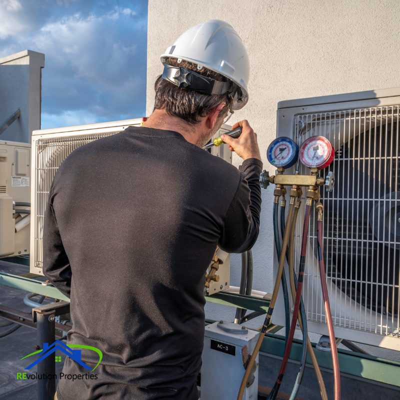 Property management technician performing HVAC system maintenance on rooftop unit
